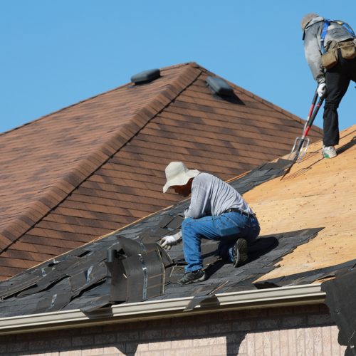 June 26, 2019 - Thornhill, Ontario, Canada: Roofers removing old asphalt shingles from the roof of a residential house in Thornhill, Ontario. Roofing in summer. Tearing down the old roof.